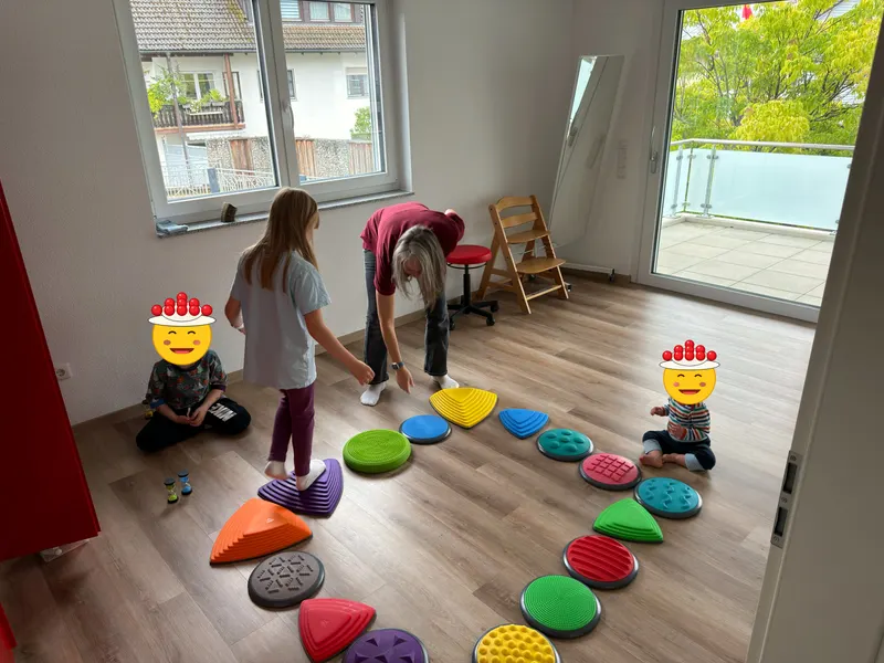 Kinder balancieren im Bewegungsraum über einen Parcours aus Therapiesteinen